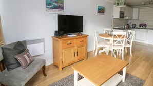 Ett vardagsrum med en TV, ett träskåp och ett matbord med stolar.