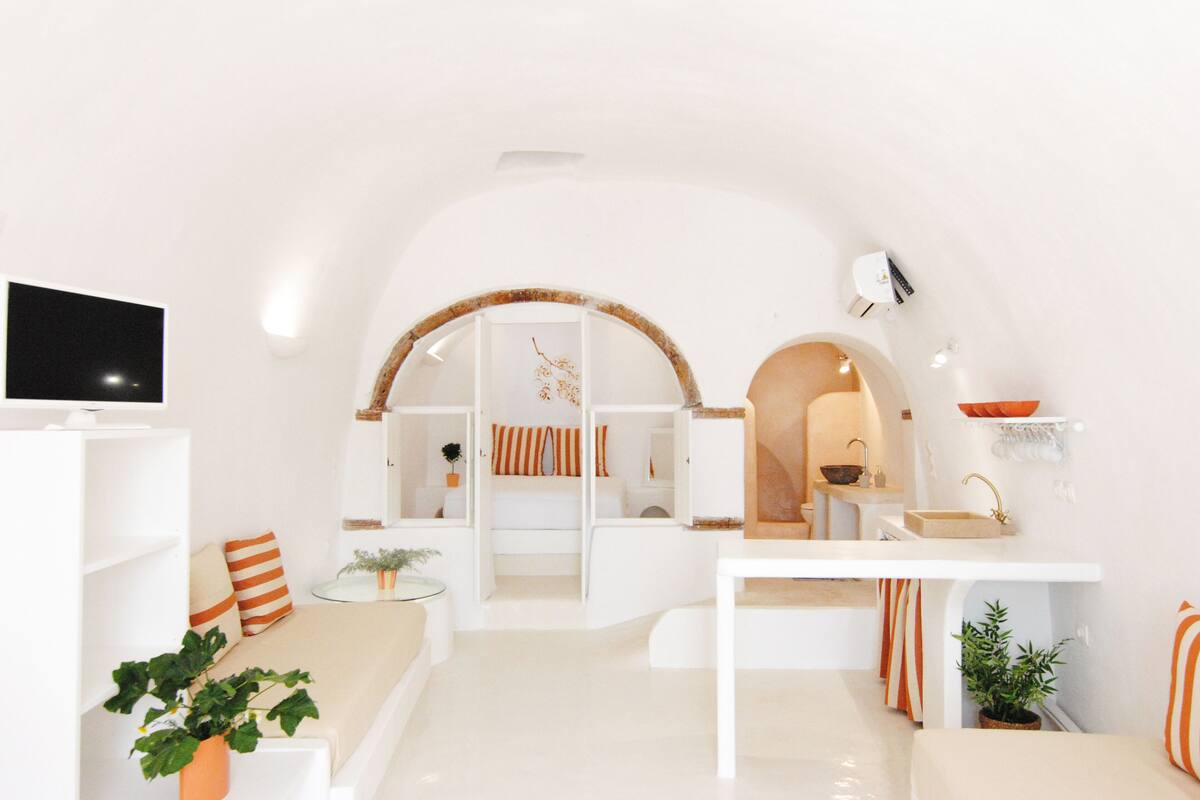 A modern, white-themed living room with a sofa, TV, and a small table.