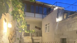Une cour dallée de pierres, un escalier et un bâtiment doté d’un balcon.
