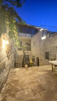 A courtyard with stone flooring, a staircase, and a building with a balcony.