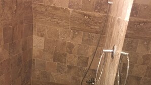 Une salle de bain avec une douche, deux toilettes et un lavabo.