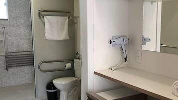 Un baño moderno con inodoro, toallero, secador de pelo y espejo.