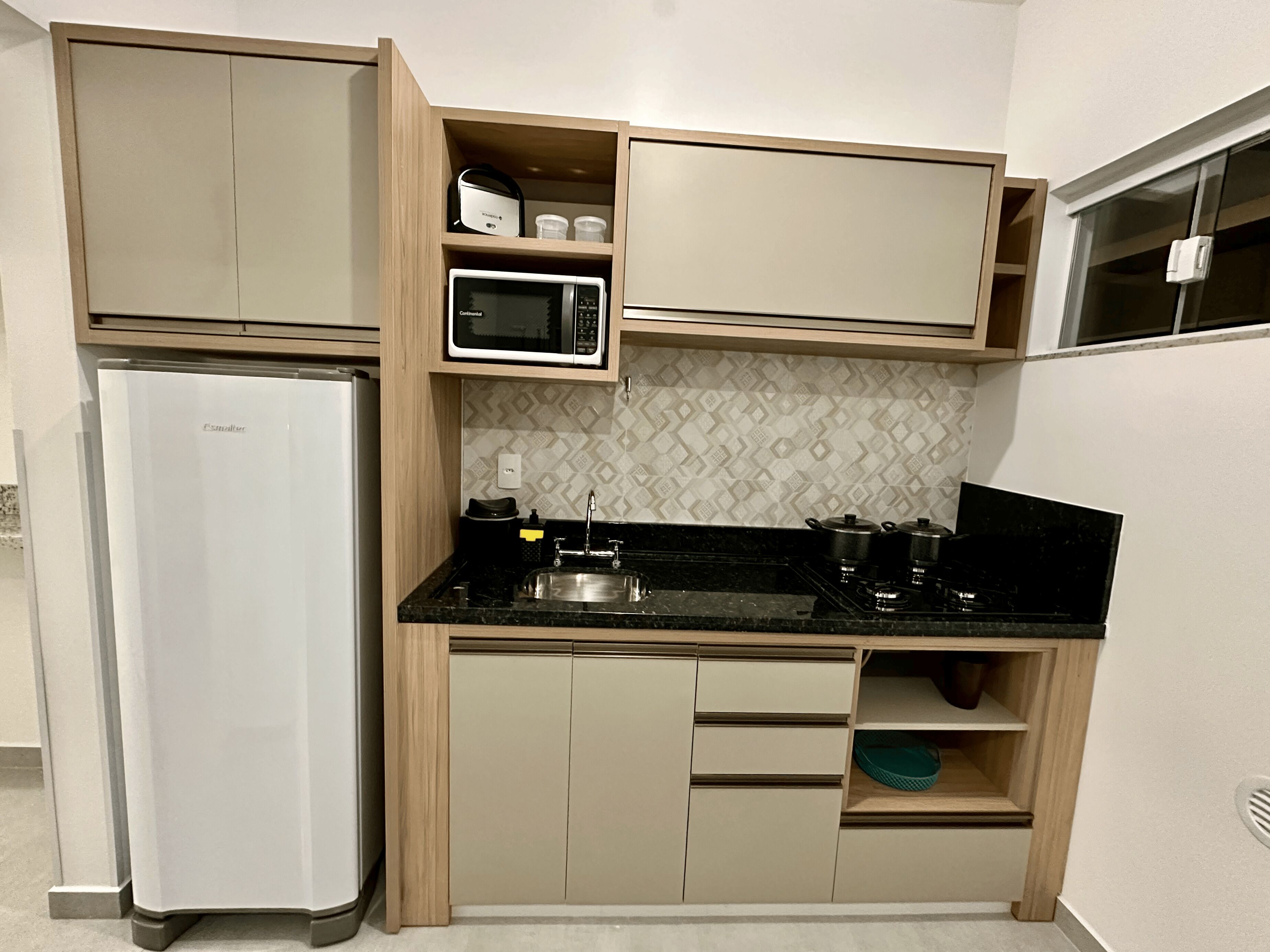 Una cocina funcional con refrigerador, microondas, estufa y gabinetes de madera.