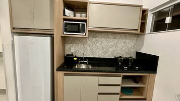 Una cocina funcional con refrigerador, microondas, estufa y gabinetes de madera.