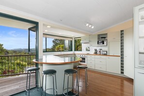 A modern kitchen with a central island, bar stools, and a view of the outdoors.