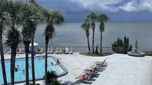 A pool area with palm trees, lounge chairs, and a view of the ocean. - Beach,Tons of entertainment, bikes, 2  golf carts, Golf, Amazing Gym, and Marina (Miramar Beach)