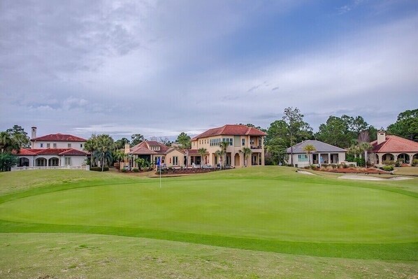 A golf course with multiple houses in the background.