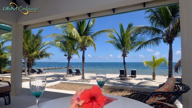 A beachside view with a table, chairs, and a decorative centerpiece. - JJEM Cabanas (Placencia)