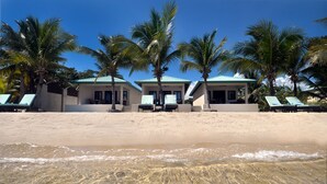 A beachfront property with two buildings, each with a covered patio and lounge chairs. - JJEM Cabanas (Placencia)