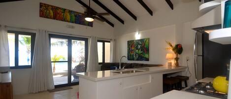 A modern kitchen with a central island, a ceiling fan, and artwork on the walls.