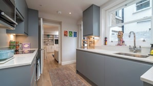 Une cuisine moderne avec des meubles gris, une grande fenêtre et un four encastré.