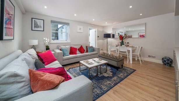 Un salon moderne avec un canapé gris, une table basse et un coin repas avec des chaises blanches.