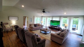 A spacious living room with a large TV, comfortable seating, and a view of the outdoors.