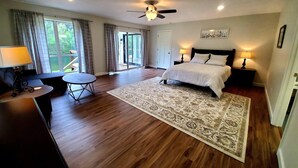 A bedroom with a bed, bedside lamps, a rug, a desk with a lamp, and a ceiling fan.