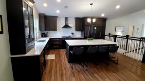 A modern kitchen with dark wood cabinets, a central island with bar stools, and a stainless steel refrigerator.