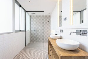 Ein modernes Badezimmer mit großem Fenster, zwei Waschbecken und einer begehbaren Dusche.