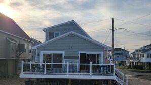A beachfront house with a covered deck and a small porch. - Cozy, year round beach cottage just steps to the water (East Haven)
