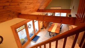 A wooden interior with a staircase, a dining area, and a sign reading "WELCOME TO THE SHORE." - Cozy, year round beach cottage just steps to the water (East Haven)