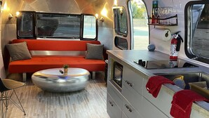 A compact, modern interior with a sofa, a round coffee table, and a kitchenette area. - Chic Airstream on a 1 acre lot on the golf course in Scottsdale (Scottsdale)