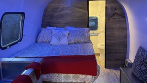 A compact, modern bedroom with a bed, bedside tables, and a small window. - Chic Airstream on a 1 acre lot on the golf course in Scottsdale (Scottsdale)