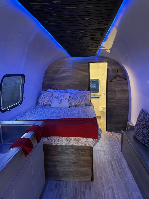 Een compacte, moderne slaapkamer met een bed, nachtkastjes en een klein raam.