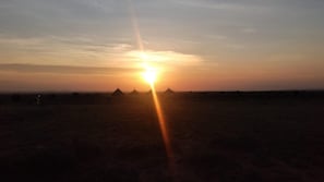Ein Sonnenuntergang über einer ebenen Landschaft mit einigen Gebäuden.
