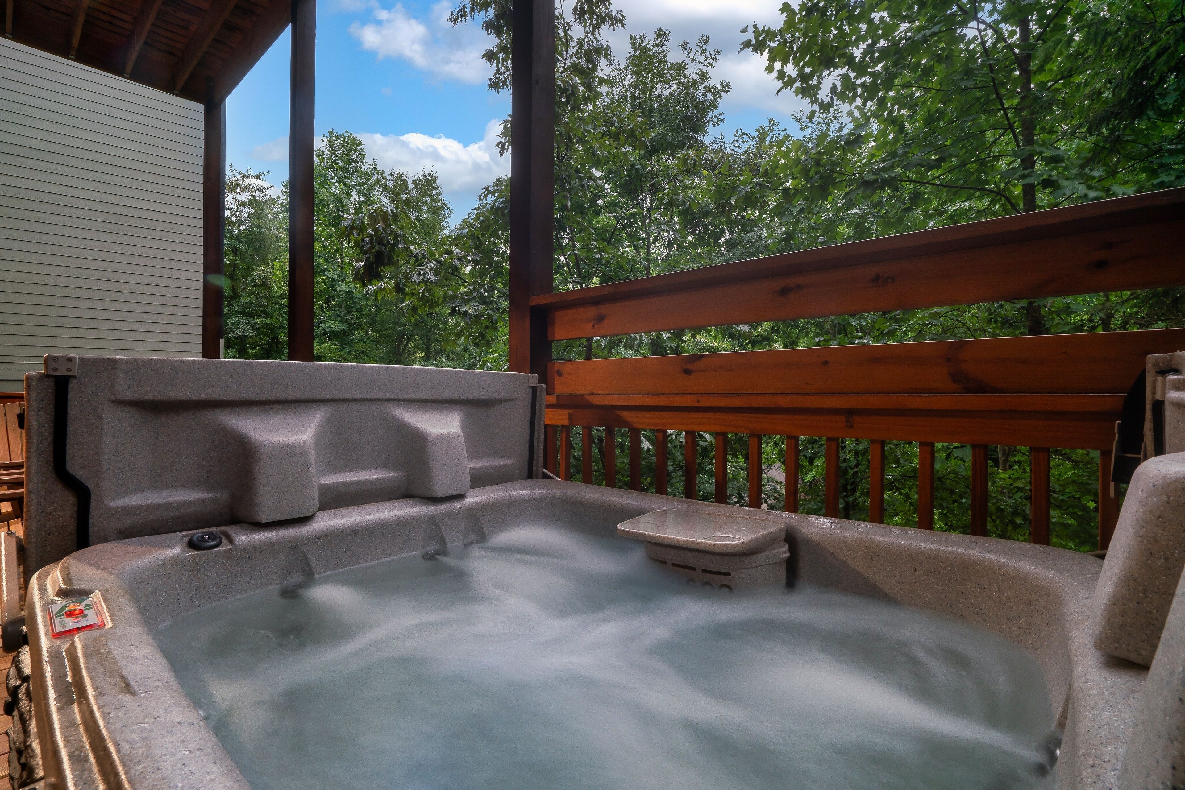 A hot tub on a wooden deck with a view of trees.