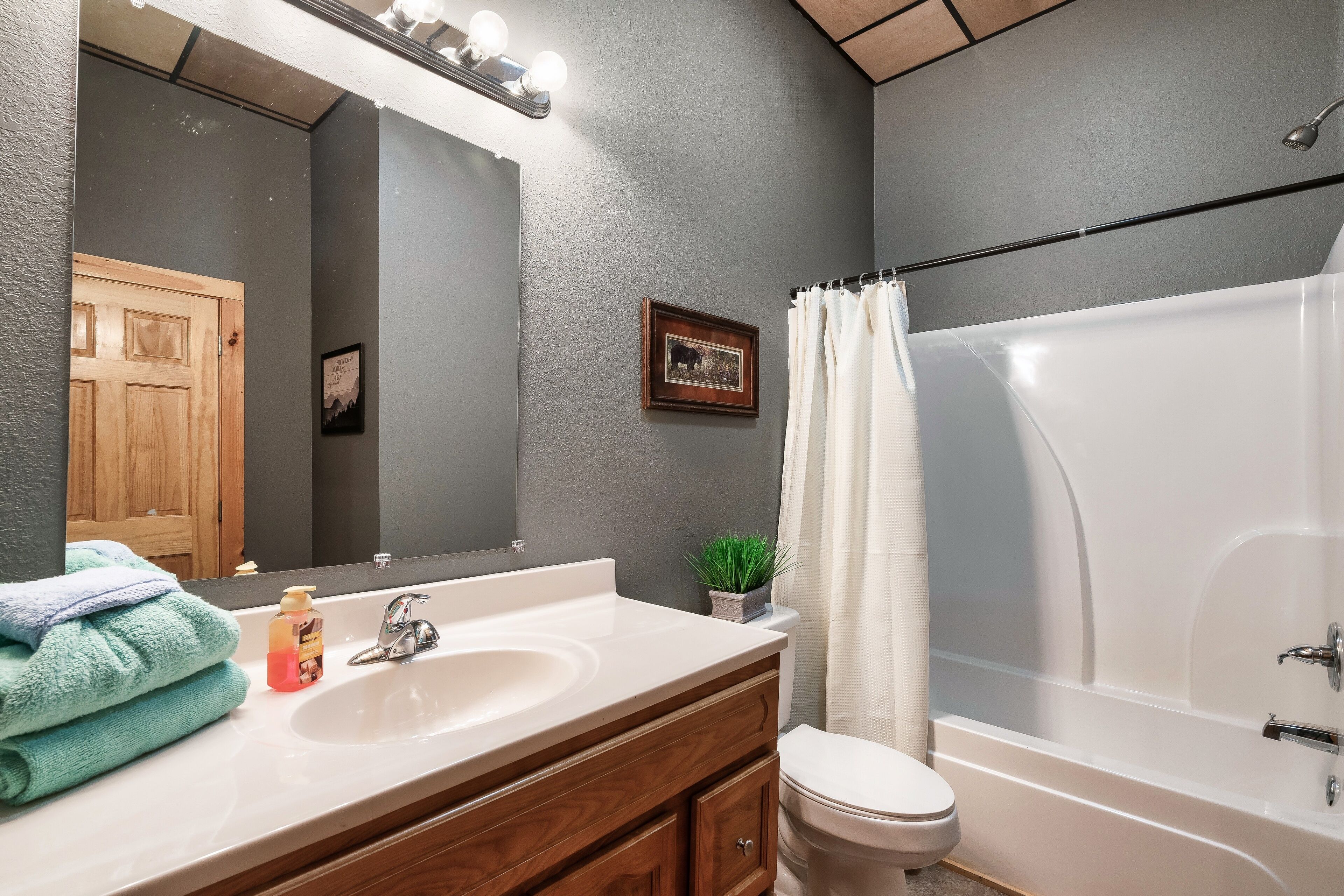 A bathroom with a white sink, wooden vanity, a toilet, and a bathtub.