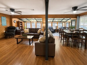 A spacious living room with a large sofa, a coffee table, and a dining area with a wooden table and chairs.