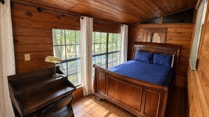 Una habitación de madera con una cama, un escritorio y una ventana.