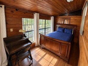 A wooden room with a bed, a desk, and a window.