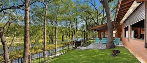 A lakeside property with a covered patio, outdoor seating, and a view of the water.