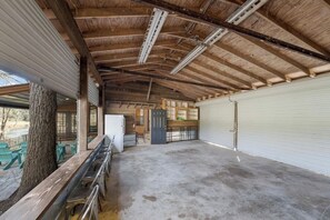 A spacious covered area with a concrete floor, wooden beams, and a large white garage door.
