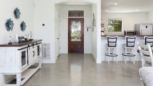 Een moderne keuken met witte kasten, een houten aanrecht en een eethoek met witte stoelen.