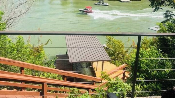 Een rivier met boten, een houten terras en een klein gebouw.