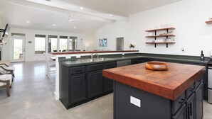 Een moderne keuken met donkere kastjes, een houten kookeiland en een groot raam.