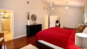 Un dormitorio con una cama grande, un ventilador de techo y una puerta que da a un baño.