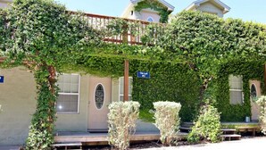Un bâtiment doté d’un porche couvert, d’une enseigne indiquant « Tiki Loft n° 2 » et d’un petit espace jardin avec des bancs.