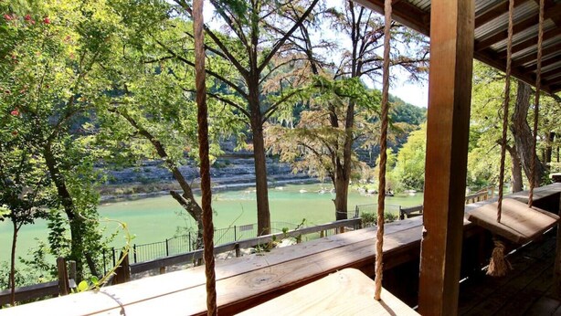 Une terrasse en bois offrant une vue sur une rivière et les arbres environnants.