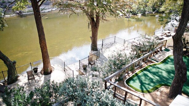 Un patio a orillas del río con asientos exteriores y vistas al río.