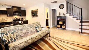 Una sala de estar moderna con un sofá, una escalera y una zona de cocina.