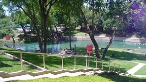 Ein Park mit Schwimmbereich, Treppen, die zum Wasser führen, und einem roten Schild mit weißer Schrift.