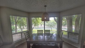Ein Essbereich mit Tisch und Bänken, großen Fenstern und einem Deckenventilator.