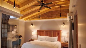 Un dormitorio con una cama grande, vigas de madera en el techo y cabina de ducha de vidrio.