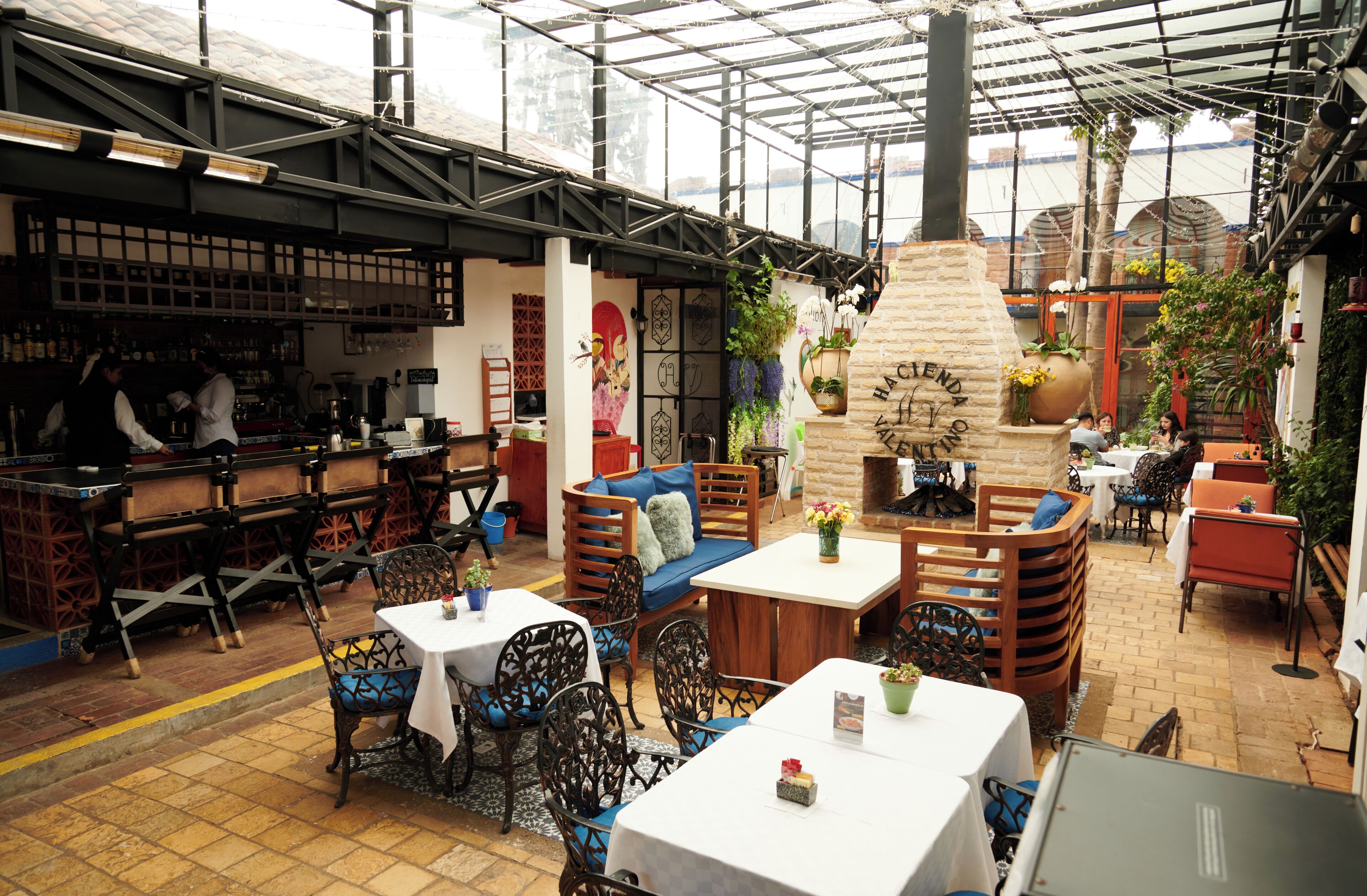 Un restaurante con área de bar, mesas dispuestas y una chimenea central.