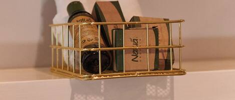 A gold wire basket on a white shelf holding bottles and a brown package.