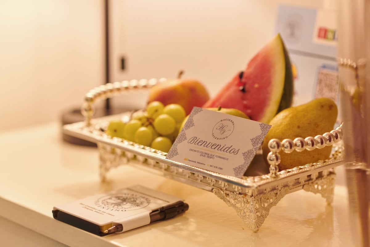 Una bandeja de frutas y una tarjeta de bienvenida sobre una mesa.