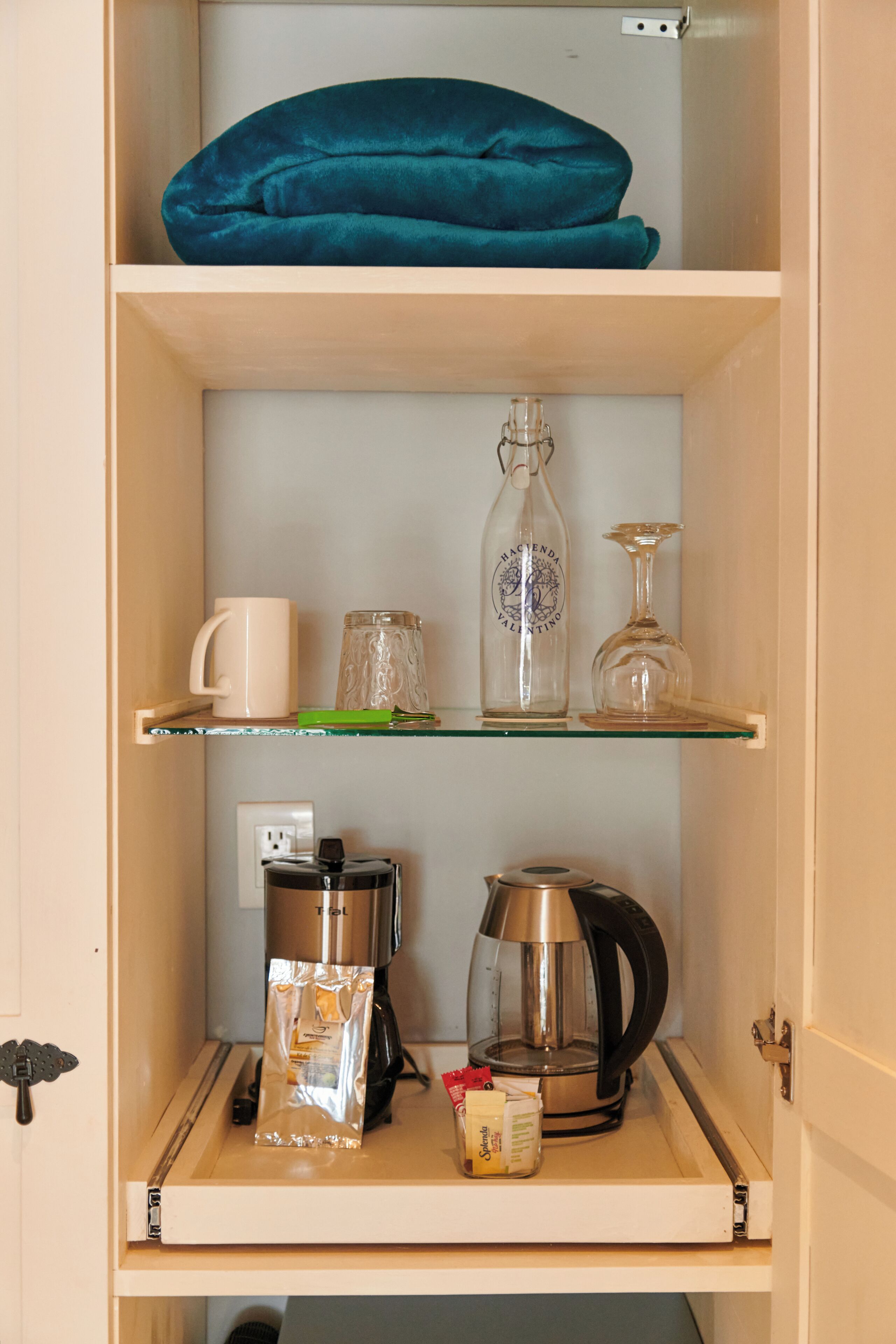 A kitchen with a coffee maker, a kettle, and a bag of coffee on the counter.