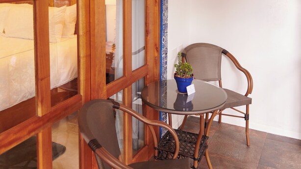 A cozy room with a wooden-framed window, a small table with two chairs, and a potted plant. - Hacienda Valentino (San Cristóbal de las Casas)