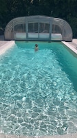 Uma piscina transparente com área de estar envidraçada.